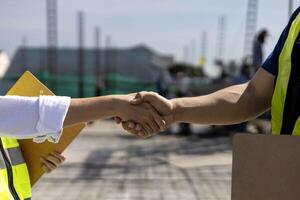 handenschudden van ingenieur in reflecterende kleding voor industrieel bedrijf transactie en vennootschap overeenkomst contract met voortdurende bouw in de achtergrond foto