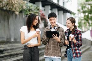 studenten zijn aan het studeren de campus park. jong mensen zijn uitgeven tijd samen. lezing boek, werken met laptop, tablet en communiceren terwijl foto