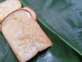 afbeelding van brood met boter, melk, suiker geplaatst Aan een banaan blad. foto