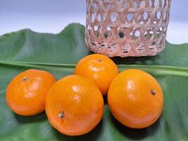 beeld van sinaasappels geplaatst in een stapel Aan banaan bladeren. foto