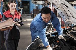 Aziatisch mannetje professioneel automotive ingenieur leidinggevende beschrijft auto motor onderhoud en reparatie werk met monteur arbeider personeel team in fix onderhoud garage, specialist beroepen in auto industrie. foto