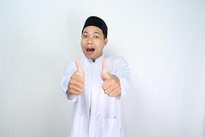 grappig Aziatisch moslim Mens geven duimen omhoog met verrast uitdrukking geïsoleerd Aan wit achtergrond foto