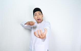 moslim Aziatisch Mens looks geschokt terwijl richten naar leeg palm geïsoleerd Aan wit achtergrond foto