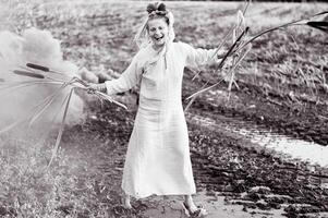 vrolijk jong vrouw met riet dansen in gekleurde rook in een veld- foto