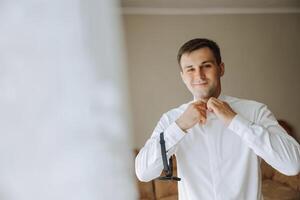 bedrijf shirt. een Mens in een wit overhemd vastmaakt de toetsen. jong politicus, mannetje stijl, zakenman knopen shirt, mannetje handen detailopname, Amerikaans, Europese zakenman foto