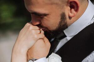 bruiloft kus. bruidegom kusjes bruid hand. trouwdag liefde. detailopname van een jong Mens zoenen zijn vrouwen hand- met goud ring terwijl maken een huwelijk voorstel. foto