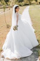 foto van de rug. een mooi jong vrouw in een wit bruiloft jurk is glimlachen Aan een warm bruiloft zomer dag