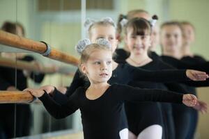 weinig meisjes Bij de ballet machine. les choreografie. jong ballerina's.. opleiding van de eerste groep Aan gymnastiek.acrobatiek les foto