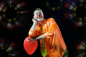 een Mens in een clown kleding met een ballon foto