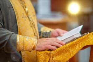 de handen van een orthodox priester houden een Bijbel foto