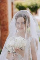 portret van een mooi jong bruid in een wit jurk met een lang sluier en een prachtig kapsel. glimlachen bruid. bruiloft dag. prachtig bruid. huwelijk. foto