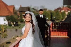 de bruid is gekleed in een elegant weelderig wit bruiloft jurk met een lang sluier en is klaar voor haar bruidegom. de eerste vergadering van de bruid en bruidegom foto