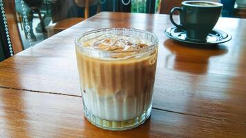 een glas van verkoudheid cappuccino Aan een houten tafel foto