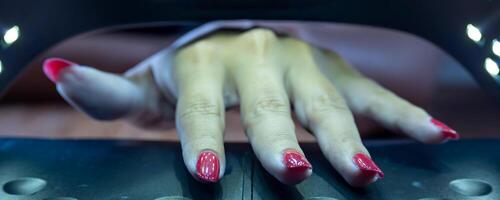 handen van een vrouw binnen de uv stand voor semi blijvend nagels. foto