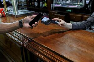 Mens betalen met zijn telefoon in een bar foto