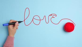 een vrouw hand- schreef liefde met een rood viltstift pen en een bal van wol foto