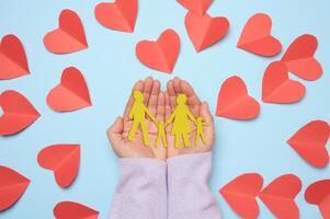 vrouw hand- Holding papier besnoeiing familie met kind, blauw achtergrond foto