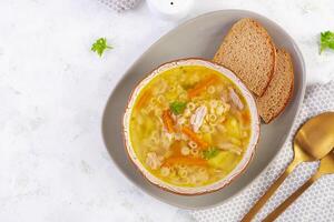 vers kip soep met groenten en stelline pasta in een kom met wortel en peterselie. top visie, vlak leggen foto