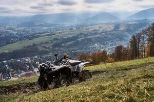 grijs quad fiets Aan de berg helling met uitzicht de stad hieronder foto