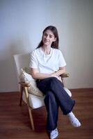 portret van een mooi tiener- meisje Aan een stoel in een helder kamer in een minimalistische stijl foto