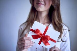 geschenk certificaat in de handen van een tiener- meisje vervelend wit pyjama met rood harten foto