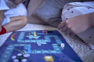 moeder met tiener- dochter en weinig zoon in pyjama spelen bord spellen Aan de verdieping foto