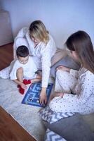 moeder met tiener- dochter en weinig zoon in pyjama spelen bord spellen Aan de verdieping foto