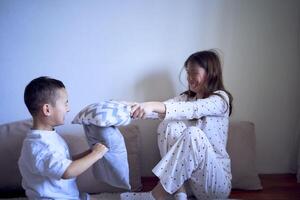 tiener- meisje en haar weinig broer zijn spelen en knuffelen in een hoofdkussen fort foto