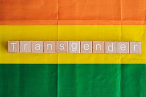 houten blokken het formulier de tekst transgender tegen een regenboog achtergrond. foto