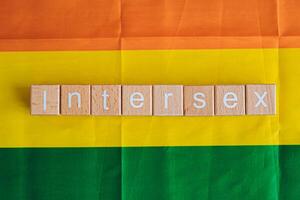 houten blokken het formulier de tekst intersekse tegen een regenboog achtergrond. foto