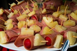 een bord van voedsel met ananas en ham Aan stokjes foto