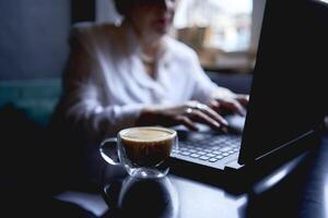 een ouderen vrouw werken in een cafe Bij een laptop foto