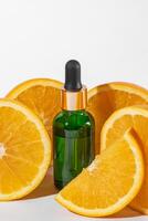 vitamine c serum in kunstmatig groen fles met druppelaar, gesneden sinaasappels Aan wit achtergrond. biologisch spa schoonheidsmiddelen met kruiden ingrediënten. foto