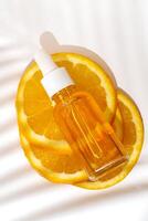 kunstmatig biologisch, vitamine c extract. plakjes van oranje en serum druppelaar fles Aan wit achtergrond met palm schaduw, top visie foto