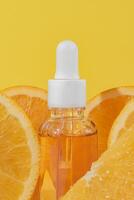 helder geel achtergrond met een druppelaar fles van citrus doordrenkt gezicht serum met vitamine c en vers oranje plakjes symboliseert huidsverzorging een uitkering. model, huid zorg. foto