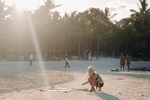 een charmant weinig meisje is aan het liegen Aan de strand en tekening Aan de zand.a weinig meisje leugens Aan de strand van de eiland van Mauritius foto