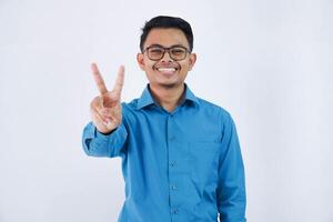 positief of gelukkig Aziatisch Mens met bril v-vormig vinger gebaar of vrede vervelend blauw overhemd geïsoleerd Aan wit achtergrond foto