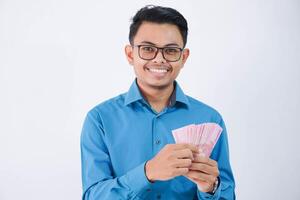 glimlach of gelukkig Aziatisch werknemer Mens met bril Holding geld vervelend blauw overhemd geïsoleerd Aan wit achtergrond foto