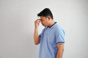 duizeligheid of depressie portret jong Aziatisch Mens Holding neus- vervelend blauw polo t overhemd geïsoleerd Aan wit achtergrond foto