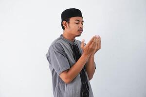 religieus jong Aziatisch moslim Mens met dichtbij ogen bidden, Holding palmen gezicht omhoog, fluisteren bidden, geïsoleerd Aan wit achtergrond. religie Islam, geloven concept foto