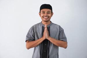 jong Aziatisch moslim Mens vervelend koko kleren glimlachen naar geven groet gedurende Ramadan en eid al fitr viering geïsoleerd Aan wit achtergrond foto