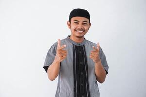 jong Aziatisch moslim Mens glimlach richten zijn beide vinger naar camera vervelend grijs moslim kleren geïsoleerd Aan wit achtergrond foto