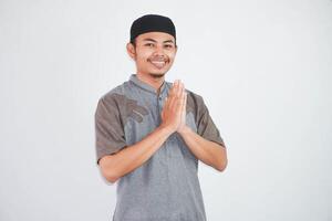 jong Aziatisch moslim Mens vervelend koko kleren glimlachen naar geven groet gedurende Ramadan en eid al fitr viering geïsoleerd Aan wit achtergrond foto