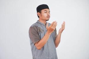 religieus jong Aziatisch moslim Mens met dichtbij ogen bidden, Holding palmen gezicht omhoog, fluisteren bidden, geïsoleerd Aan wit achtergrond. religie Islam, geloven concept foto