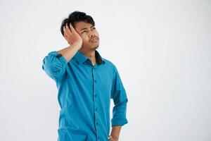 duizeligheid of spanning portret jong Aziatisch Mens Holding hoofd vervelend blauw overhemd geïsoleerd Aan wit achtergrond foto