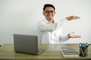 jong Aziatisch zakenman in een werkplaats Holding kopiëren ruimte naar insert een advertentie, vervelend wit overhemd met bril geïsoleerd foto