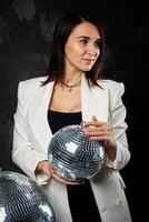 portret van een vrouw Holding een zilver disco bal. genomen in een foto studio.