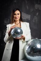 portret van een vrouw Holding een zilver disco bal. genomen in een foto studio.