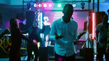 mannetje persoon feesten met vrienden in discotheek, hebben pret Aan elektronisch muziek- Bij nachtclub. jong volwassen dansen en jumping in de omgeving van Aan dans vloer, funky modern viering. handheld schot. foto