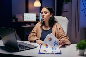 zakenvrouw op zoek in laptop toezicht houden op proberen naar vind oplossingen. vrouw controle aantekeningen Aan klembord terwijl werken Aan belangrijk project aan het doen na een tijdje. foto